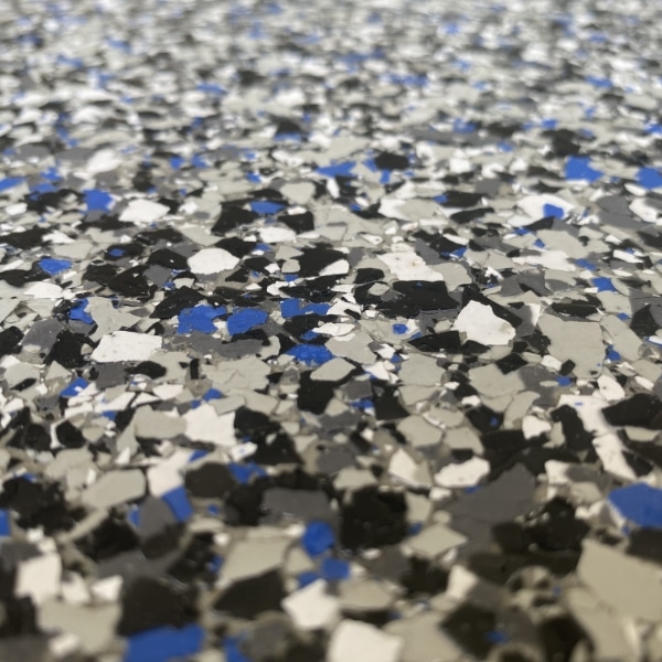 A close-up image of a speckled surface with black, white, gray, and blue flecks, possibly a terrazzo floor or countertop.